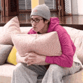 a person sitting on a couch with a pillow and a supreme hat