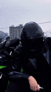 a person wearing a black helmet is standing next to a green motorcycle