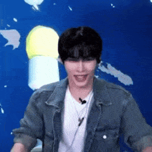 a man wearing a denim jacket and a white t-shirt is laughing .