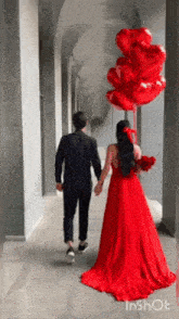 a woman in a red dress is holding a bunch of balloons