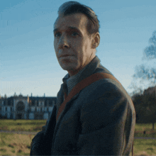 a man in a grey coat stands in front of a building