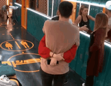 a man is hugging a woman in a hallway with a sign on the floor that says toilets