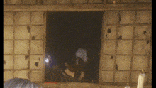 a person is standing in a dark room looking out a window
