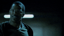 a man wearing glasses and a black shirt is standing in the dark