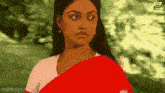 a woman wearing a red saree and a white shirt looks at the camera .