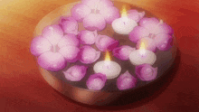 a bowl filled with purple flowers and candles on a table .