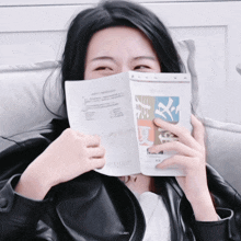 a woman covering her face with a book with chinese writing on the cover
