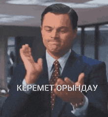 a man in a suit and tie is clapping his hands in a room