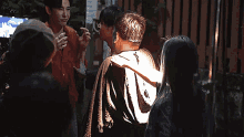 a group of people are standing in front of a wooden fence and talking to each other