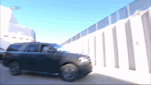 a black suv is parked in front of a fence with the letters aow on the bottom left