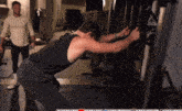 a man in a black tank top is using a machine in a gym with a youtube logo in the corner