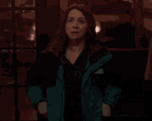 a woman wearing a green jacket is covering her mouth with her hand .