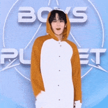 a young man in a hoodie stands in front of a boys planet logo