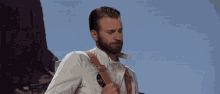 a man with a beard wears a white jacket with a brown strap