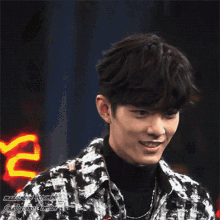 a young man wearing a plaid jacket and a black turtleneck is making a funny face .