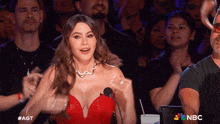 a woman in a red dress stands in front of a microphone with nbc written on the bottom of the screen