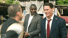 three men in suits and ties are standing next to each other in front of a sign that says prime on it