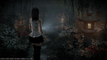 a woman in a white top and black skirt walks through a forest