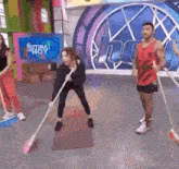 a group of people are standing on a stage holding brooms and cleaning the floor .