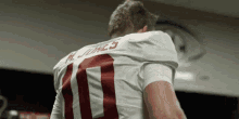 a football player with the number 11 on his jersey is standing in a locker room .