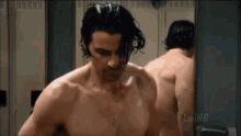 a shirtless man is standing in front of a mirror .