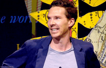 a man wearing a blue jacket and a grey shirt is smiling in front of a sign that says the lost smiles