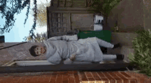 a person in a white robe is laying on a brick sidewalk