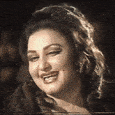 a close up of a woman 's face smiling in a black and white photo