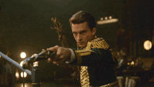 a man in a green and gold uniform holds a sword in his right hand