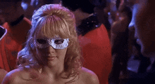 a woman wearing a masquerade mask is standing in a crowd of people .