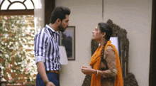 a man and a woman are standing next to each other in a living room and looking at each other .