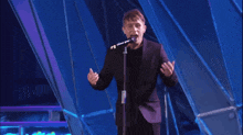 a man in a suit singing into a microphone on stage