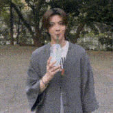 a young man in a kimono is drinking from a cup through a straw .