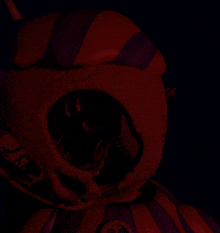 a red and purple stuffed animal with a smiley face on its chest