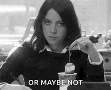 a woman is sitting at a table holding a tea bag in her hand .