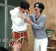 a man in a striped shirt is laughing with another man in a white shirt