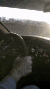 a person is driving a car with the sun shining through the window
