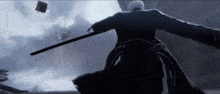 a man in a black suit is holding a sword in his hand .