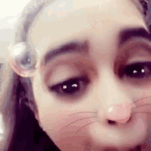 a close up of a woman 's face with a cat nose and soap bubbles in her eyes .