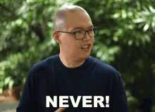 a man wearing glasses and a blue shirt says " never "