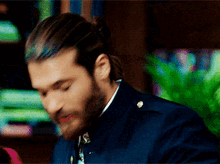 a man with long hair and a beard is wearing a blue uniform