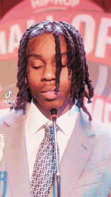 a man in a suit and tie is speaking into a microphone .