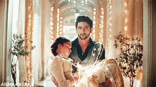 a man is carrying a woman in his arms with a string of lights around them