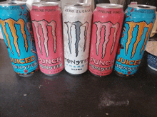 five cans of punch monster energy drinks are lined up on a table