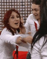 a woman with red hair is hugging a man in a white shirt