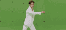 a man in a white suit is standing in front of a green screen without a shirt on .