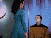 a woman in a blue dress stands next to a man in a yellow uniform