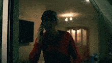 a woman in a red shirt is talking on her cell phone