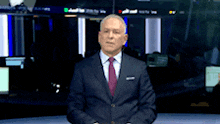 a man in a suit and tie is standing in front of a screen that says ' abc ' on it