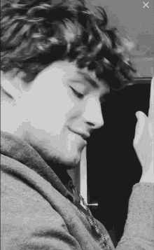 a black and white photo of a young man with curly hair and a hoodie
